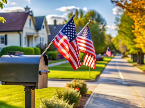 A singular mailbox stands alone on a quiet suburban street, adorned with patriotic flags, awaiting the arrival of an important election ballot envelope